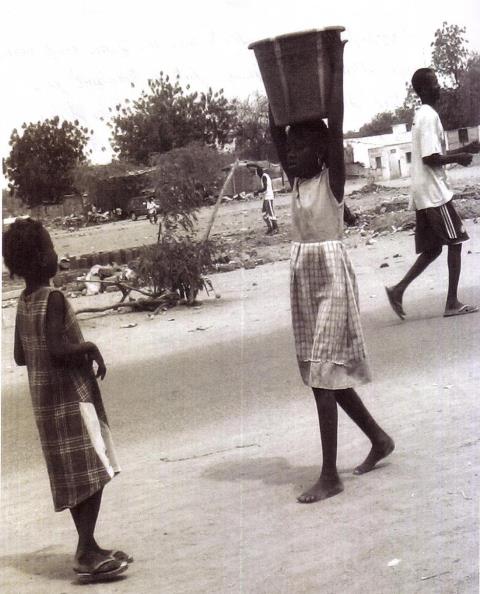 fille portant de l'eau pour sa famille d'acceuil